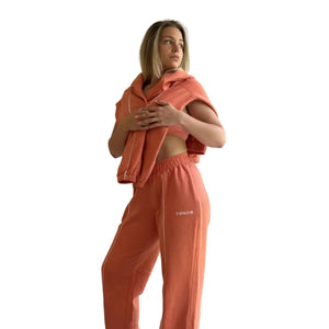 Woman wearing a peach-colored outfit standing in a room with a window.