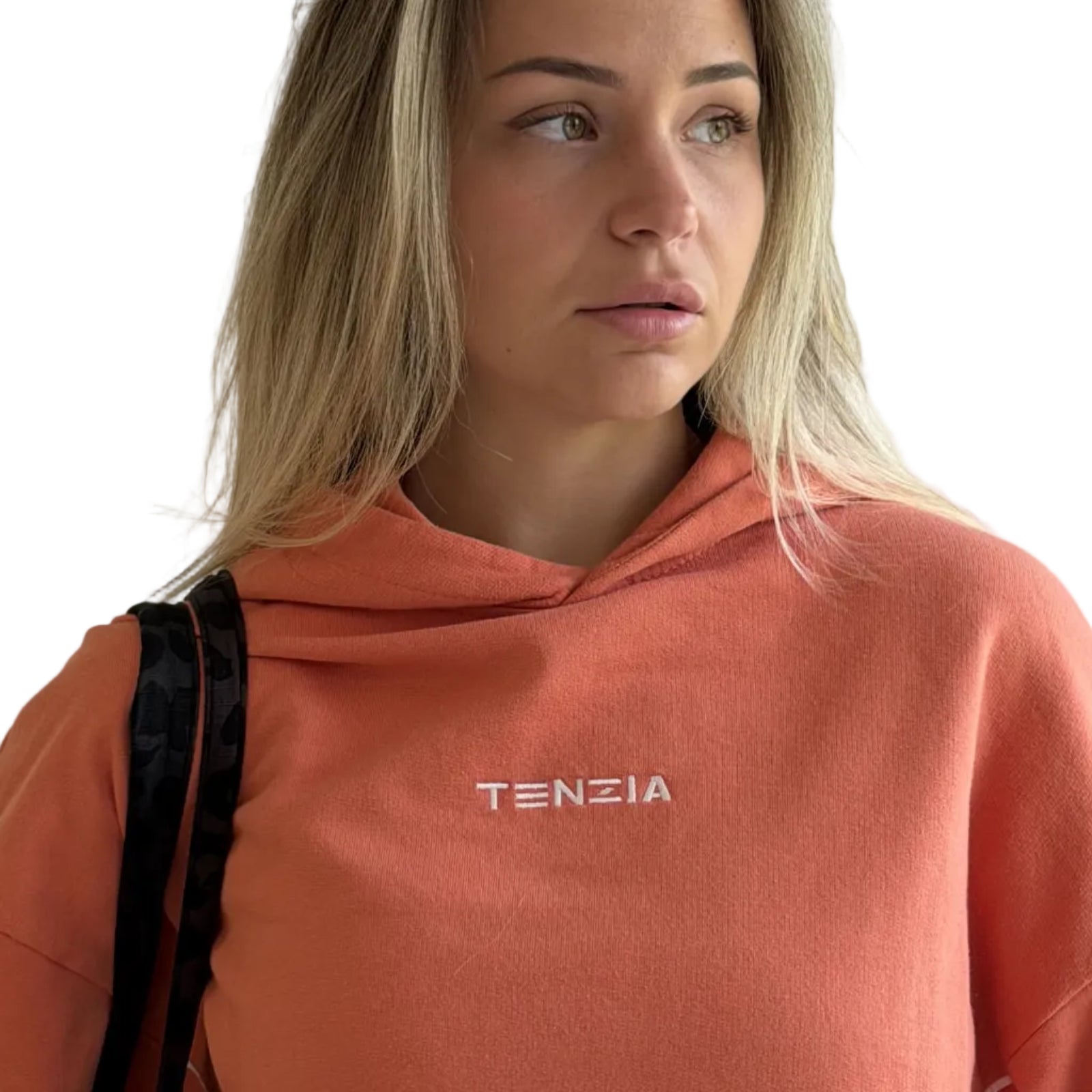 Person wearing a peach-colored hoodie with 'TENZIA' branding against a plain background